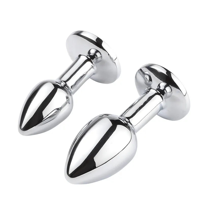 A trio of polished metal anal plugs featuring vibrant colored rhinestones on a white background