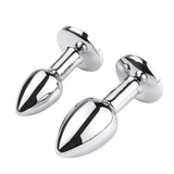 A trio of polished metal anal plugs featuring vibrant colored rhinestones on a white background